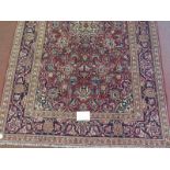 A Persian Ardkan carpet central heavy floral patterns on red ground with wide blue borders. In