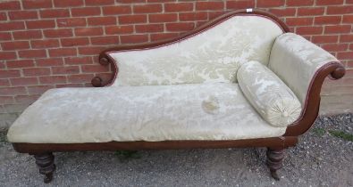 A Victorian mahogany chaise longue with scrolled back, upholstered in cream damask material with