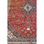 A central Persian Kashan carpet with central blue motif on red ground. 320cm x 220cm. Condition