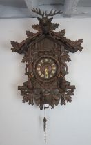 A large well carved antique black forest cuckoo clock, the canopy surmounted by a stag’s head