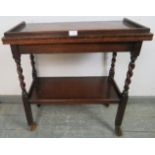 A 1920s oak two-tier drinks trolley/turnover card table, the top with ¾ gallery, opening onto a