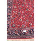 A large mid 20th century Persian carpet, floral pattern on a red ground with deep blue on red