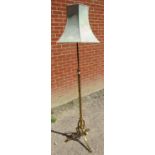 An Arts & Crafts brass height adjustable standard lamp, on a scrolled tripod base with pad feet.