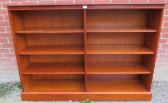 A large yew wood low open bookcase, housing six height adjustable shelves with reeded edges, on a