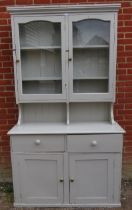 An antique pine kitchen dresser painted grey, the glazed doors opening onto two fitted shelves,