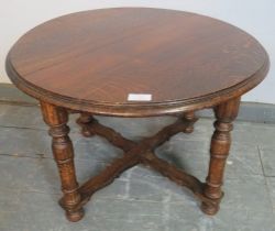 An antique oak low circular side table, on tapering supports with a shaped ‘X’ stretcher. H42cm