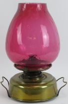 A large Edwardian Sherwood’s Sun round wick brass oil lamp with honeycomb pattern cranberry glass