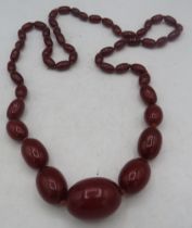 A cherry amber graduated individually knotted necklace. Centre amber approx 30mm x 24mm, length