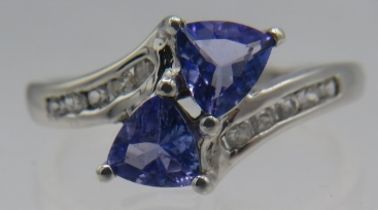 A 9ct white gold cross over ring set with two faceted trilliant cut tanzanite's, approx 6mm each,