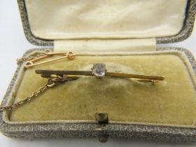A yellow metal single diamond bar brooch with safety chain, approx 0.25cts, boxed. Approx weight 4.2