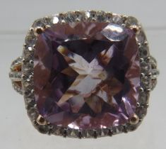 A silver gilt ring set with a large faceted cushion cut amethyst edged with white stones and white