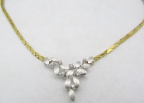 An 18ct yellow & white gold delicate necklace. The centre design having leaf decoration and set with