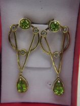 A pair of silver gilt earrings set with faceted pear and round cut peridot stones, with three