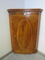 A George III flame mahogany hanging corner cupboard of excellent colour, strung with satinwood and
