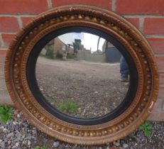 A 19th century convex butler’s mirror, having a reeded ebony border within an ornate gilt gesso