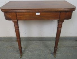 A Georgian mahogany turnover tea table, with reeded edge, on tapering turned supports with brass