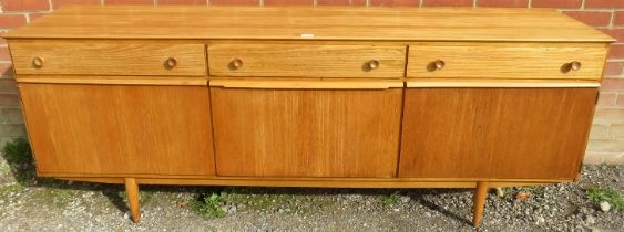 A mid-century ash sideboard, housing three short drawers with turned wooden handles, above a fall