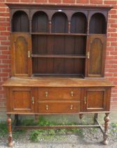 A solid oak reproduction Welsh dresser in the 18th century taste, having an arcaded canopy above