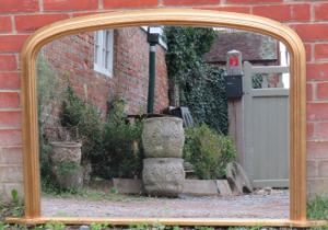 A 19th century style giltwood arched overmantle mirror, on a shaped plinth base. H83cm W125cm