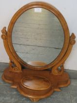 A Victorian walnut oval swing vanity mirror, having acanthus carved and pierced uprights, on a