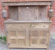 An antique stripped oak court cupboard in the Elizabethan taste, having a relief carved frieze above