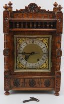 A Black Forest carved oak mantel clock, late 19th/early 20th century. The dial with silvered Roman
