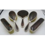 A five piece silver and tortoiseshell dressing table set comprising hand mirror, two hair brushes