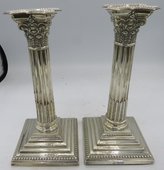 A pair of silver Corinthian column candlesticks on square bead edged base, Sheffield 1912. Approx