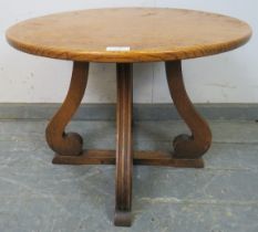 An early 20th century oak low side table, circular top on scrolled supports and cross-stretcher.
