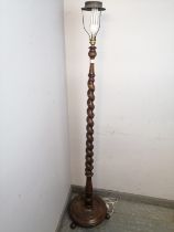 An antique mahogany standard lamp, the tapering barley twist column on a dished
