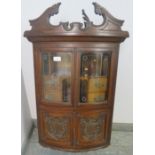An Edwardian ornately carved mahogany bow front hanging wall cabinet, shaped pediment above etched