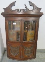 An Edwardian ornately carved mahogany bow front hanging wall cabinet, shaped pediment above etched