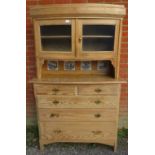 A 19th century stripped pine bowfront cabinet on chest, having two glazed panelled doors above