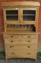 A 19th century stripped pine bowfront cabinet on chest, having two glazed panelled doors above