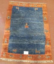 An Eastern thick wool rug. Central block blue with styalised figure & animals and bordered in