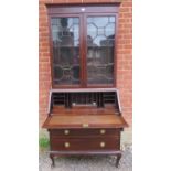 An Edwardian mahogany bureau bookcase, having twin astral glazed doors enclosing adjustable shelves,