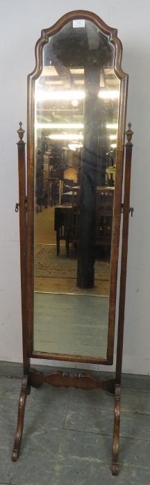 A turn of the century walnut cheval mirror, within a shaped surround, the uprights with turned