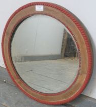 A turn of the century circular bevelled wall mirror, within a stripped oak frame with beaded red