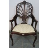 An Edwardian mahogany open sided armchair, having a very ornately carved and pierced back, the