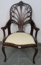 An Edwardian mahogany open sided armchair, having a very ornately carved and pierced back, the