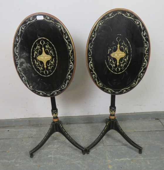 A pair of French Empire style ebonised oval tilt-top tables, hand-painted with Classical motifs