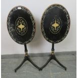 A pair of French Empire style ebonised oval tilt-top tables, hand-painted with Classical motifs