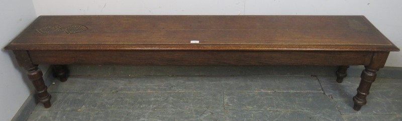 An unusually long 19th century oak hall bench/window seat, carved decoration to one end of seat,