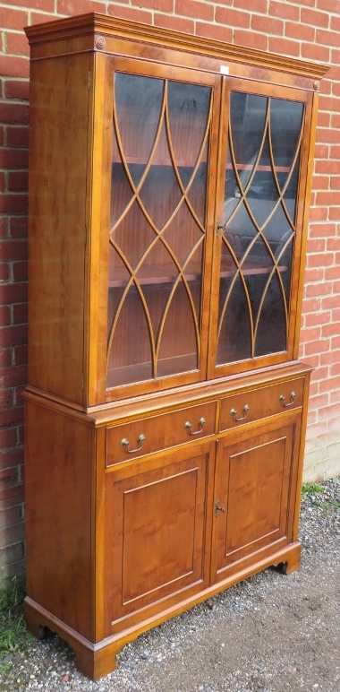 A reproduction yew wood tall glazed bookcase, having tracery doors opening onto two height- - Image 2 of 2
