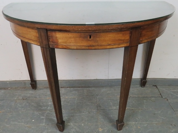 A Georgian mahogany demi-lune serving table strung with ebony, housing three blind drawers, on