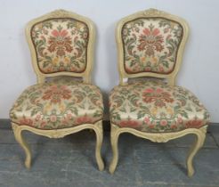 A pair of vintage French side chairs in the Louis XV style, cream painted carved wood frames,