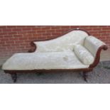 A Victorian mahogany chaise longue with scrolled back, upholstered in cream damask material with