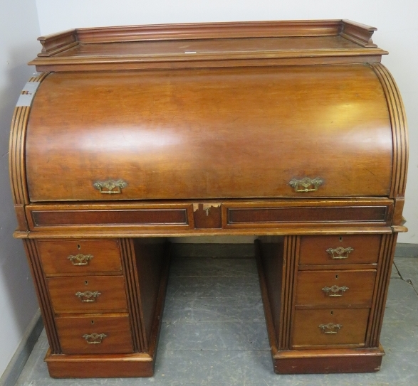A 19th century roll top desk, having 3/4 gallery top above the revolving cylinder enclosing