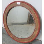 A turn of the century circular bevelled wall mirror, within a stripped oak frame with beaded red