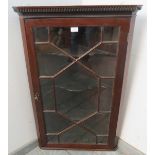 A Georgian mahogany glazed corner cupboard, with dentil cornice, the astral glazed door opening onto